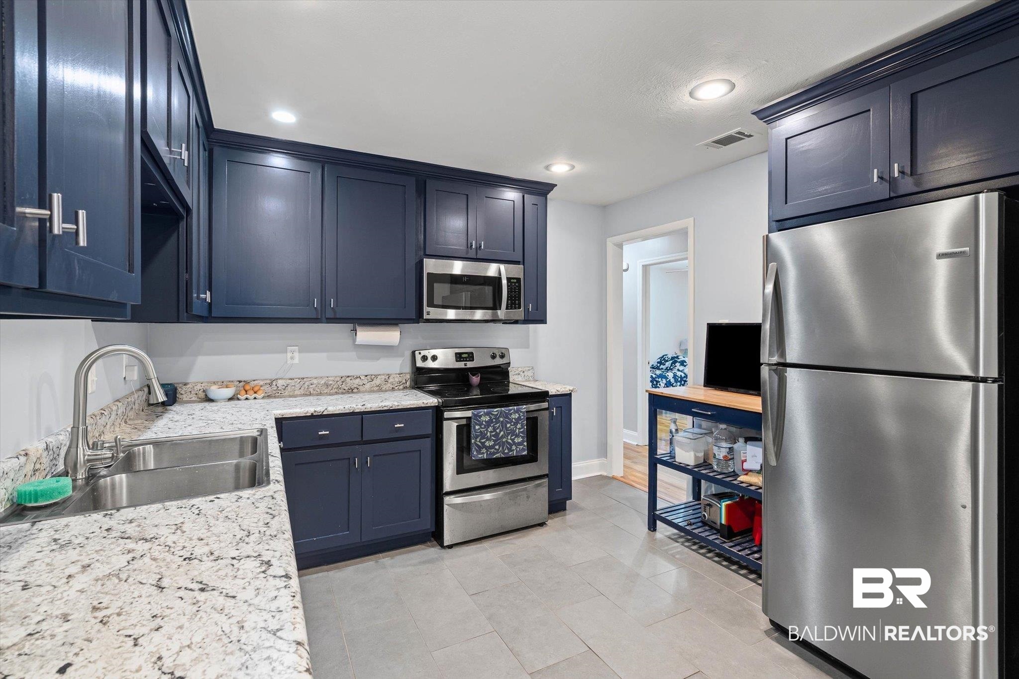 Kitchen with navy cabinets, granite counters, and stainless steel appliances.