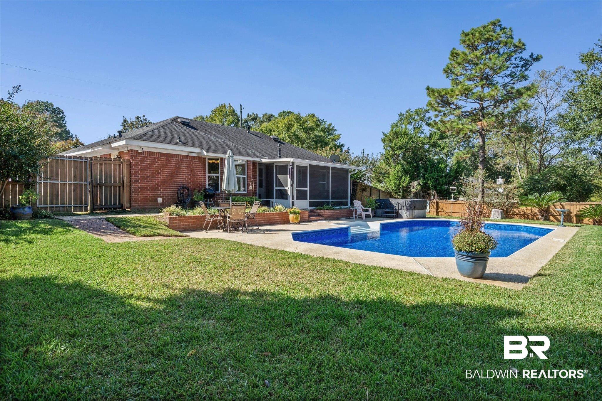 Brick home backyard with a screened porch, swimming pool, and patio dining area.