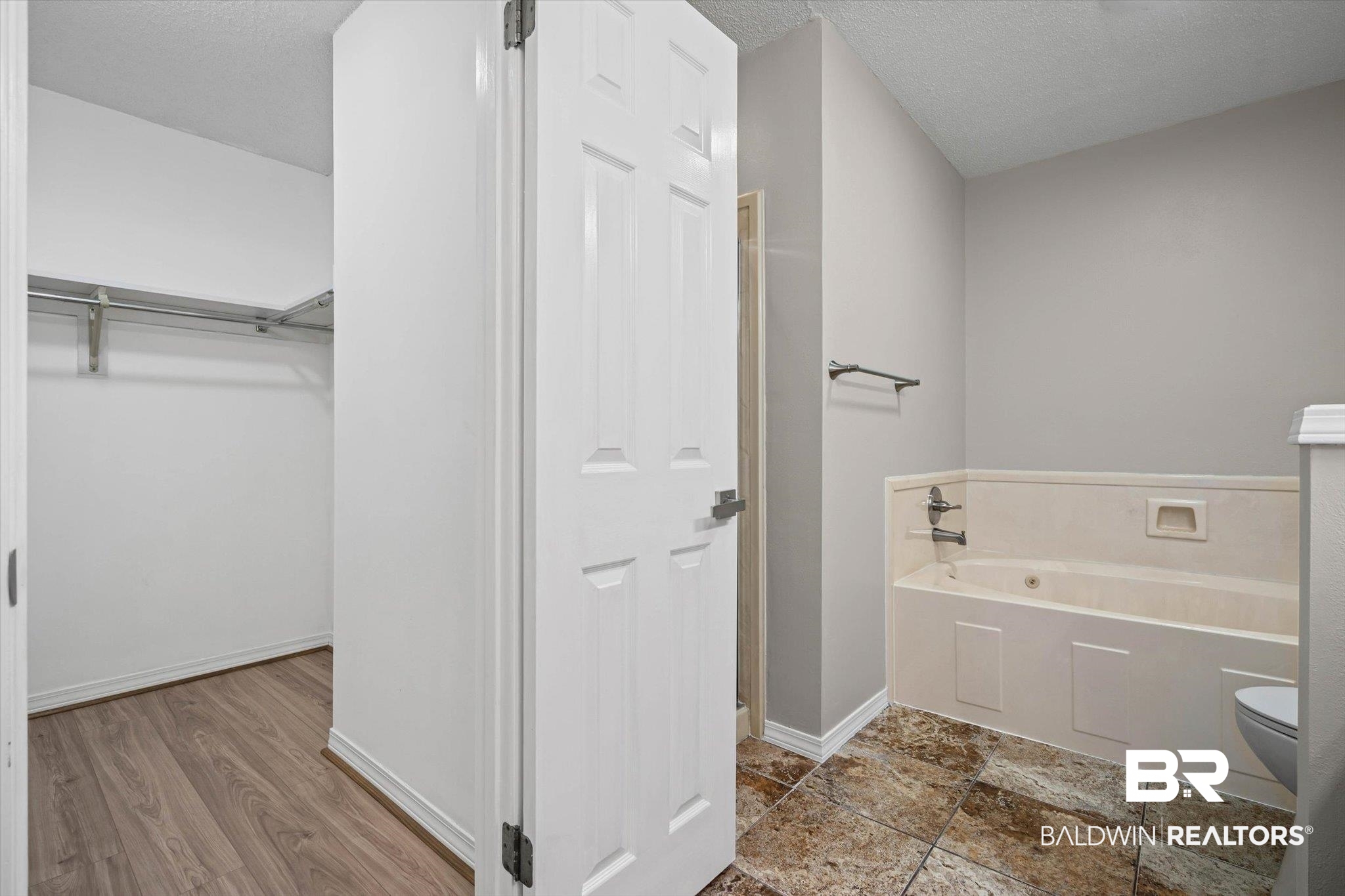 Bathroom with a built-in tub and tiled floor beside an open walk-in closet.