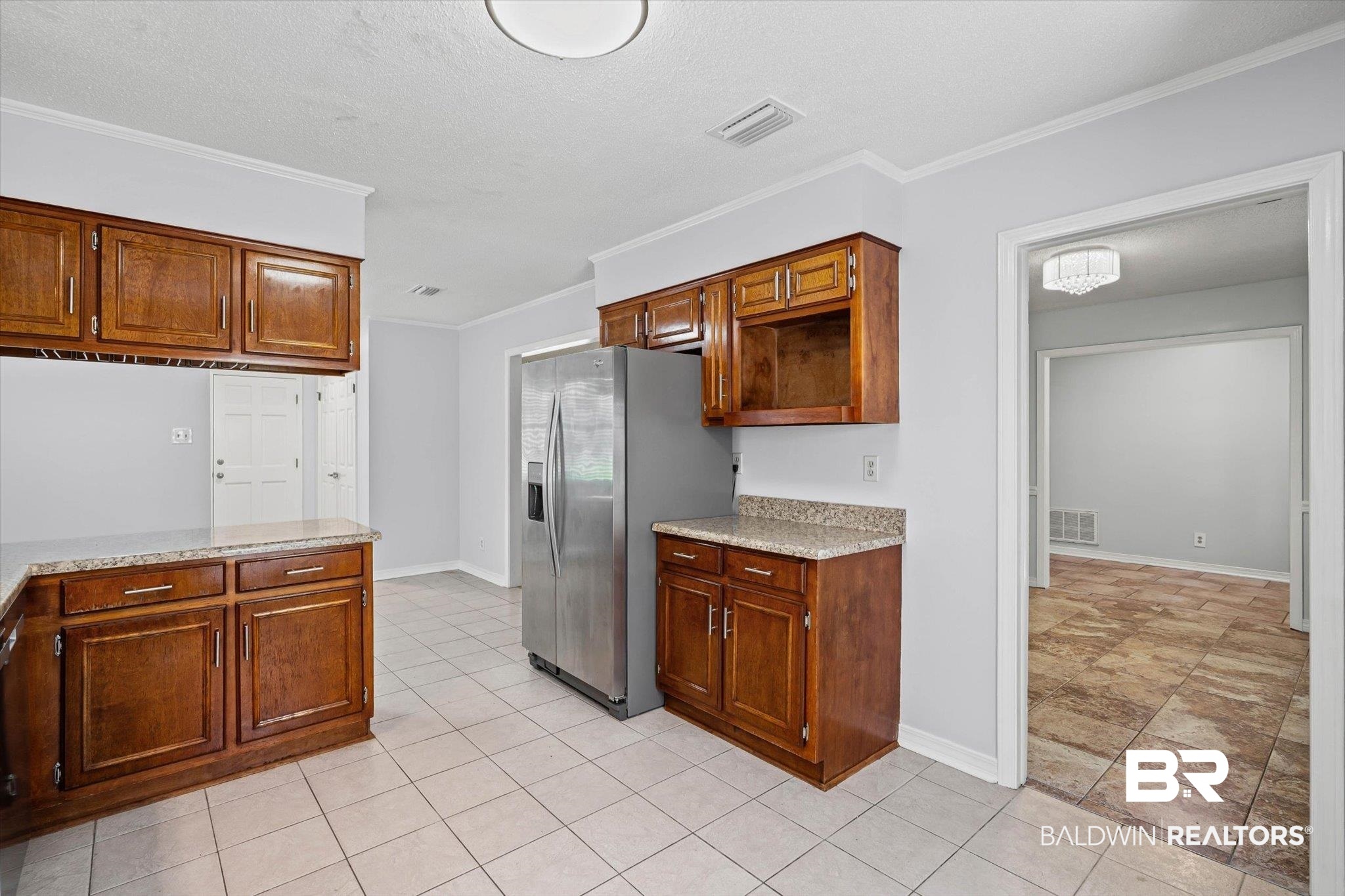 Kitchen with dark wood cabinetry, granite countertops, and a stainless steel refrigerator.