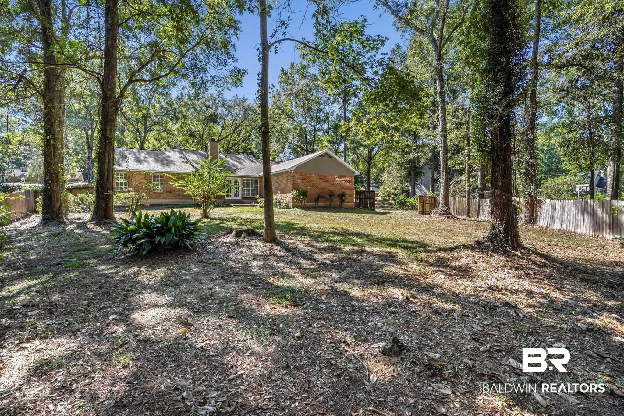 Brick ranch house viewed from the wooded, leaf-strewn backyard.