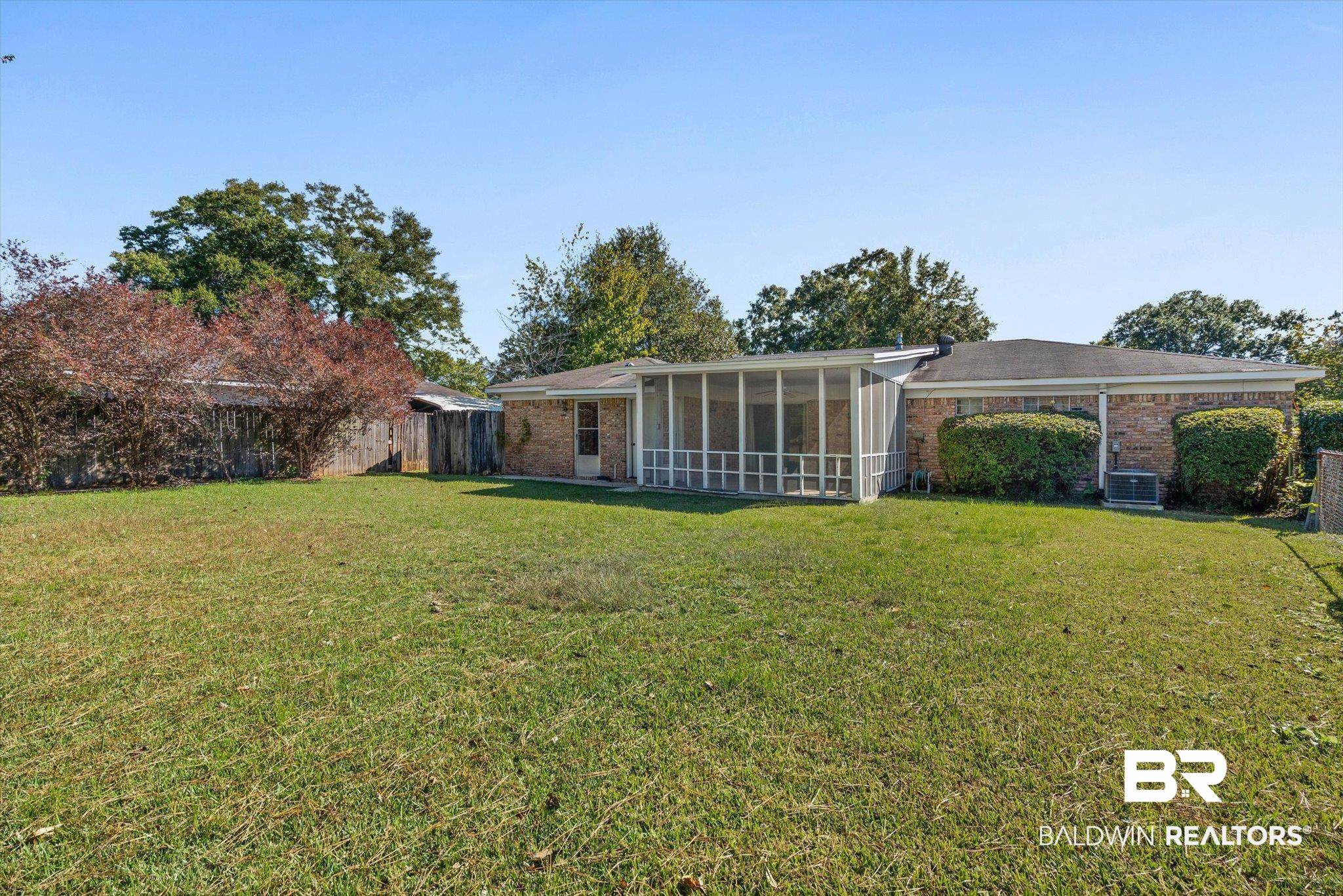 Brick home with a screened porch and broad grassy backyard.
