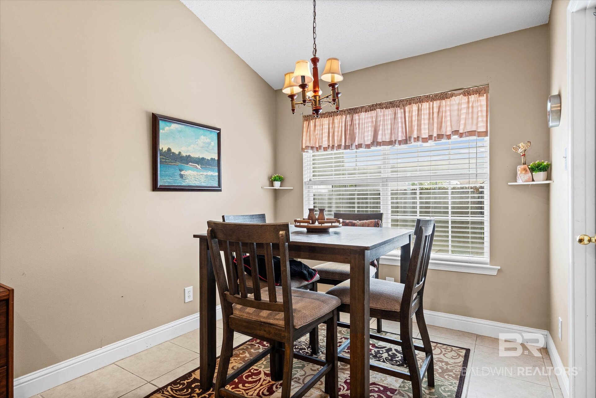 Dining room with a dark wood table, patterned rug, and large window with blinds.