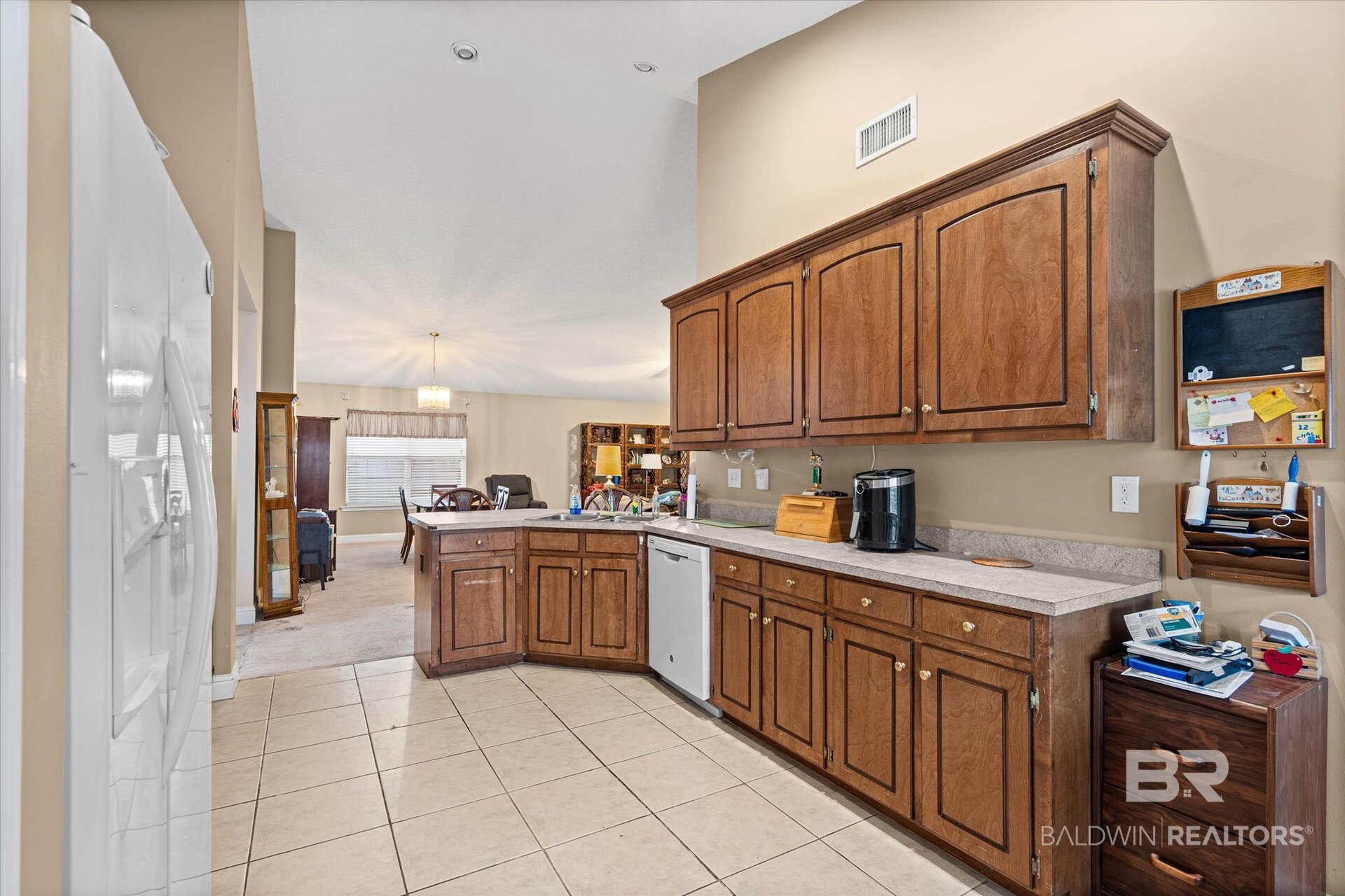 Kitchen with dark wood cabinetry, long counters, tiled floors, and an adjoining dining area.