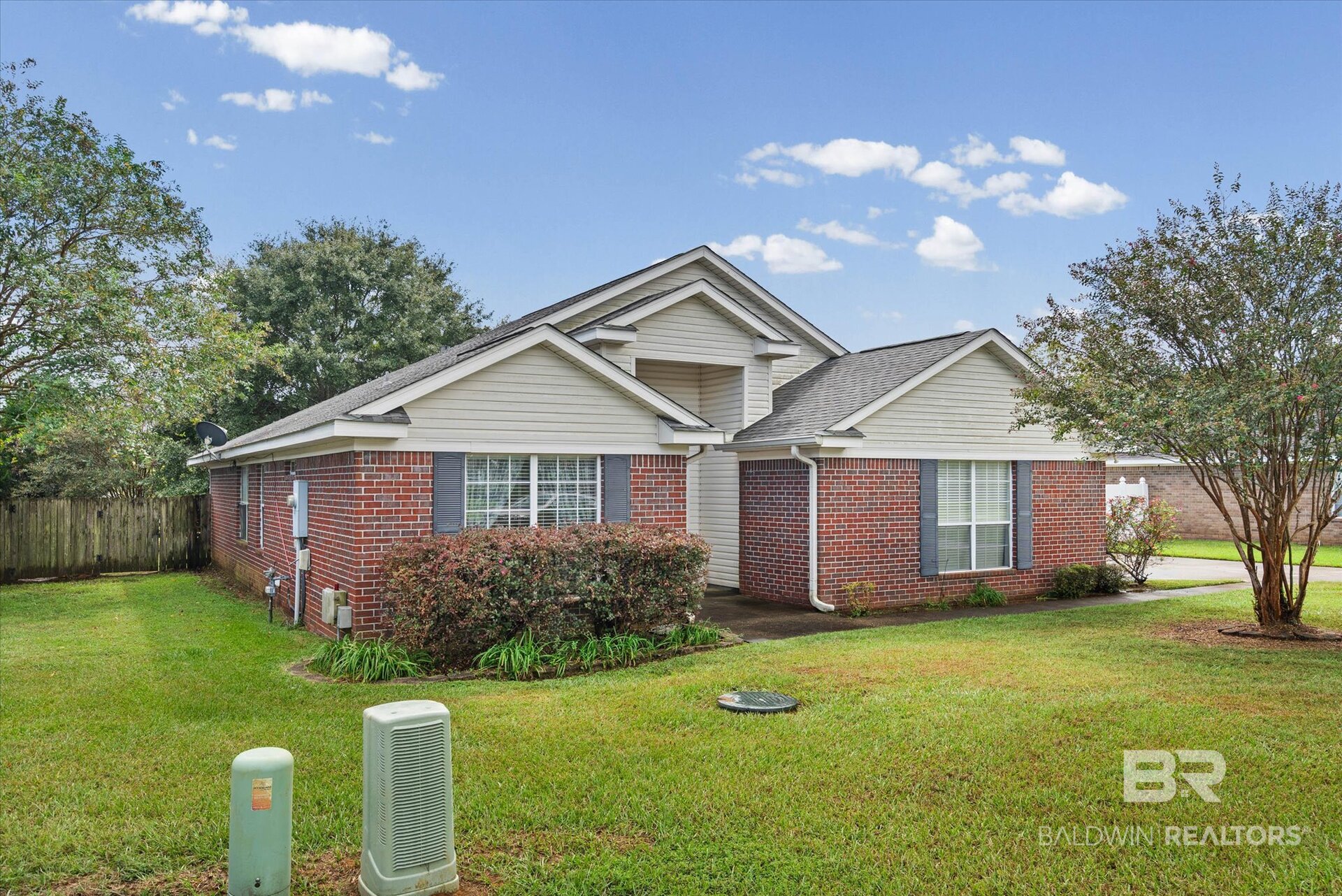 Brick house with white siding, multiple gables, dark shutters, and a green lawn.