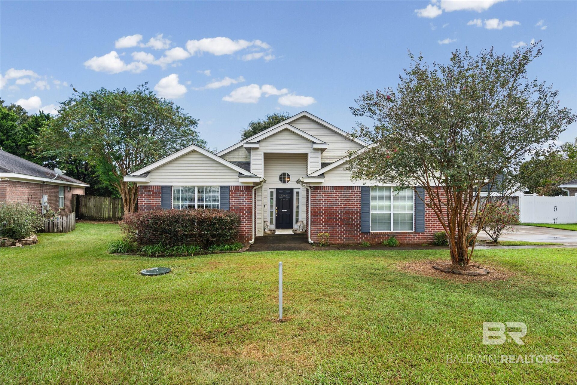 Brick-and-siding house with a covered entry, broad lawn, and mature trees.