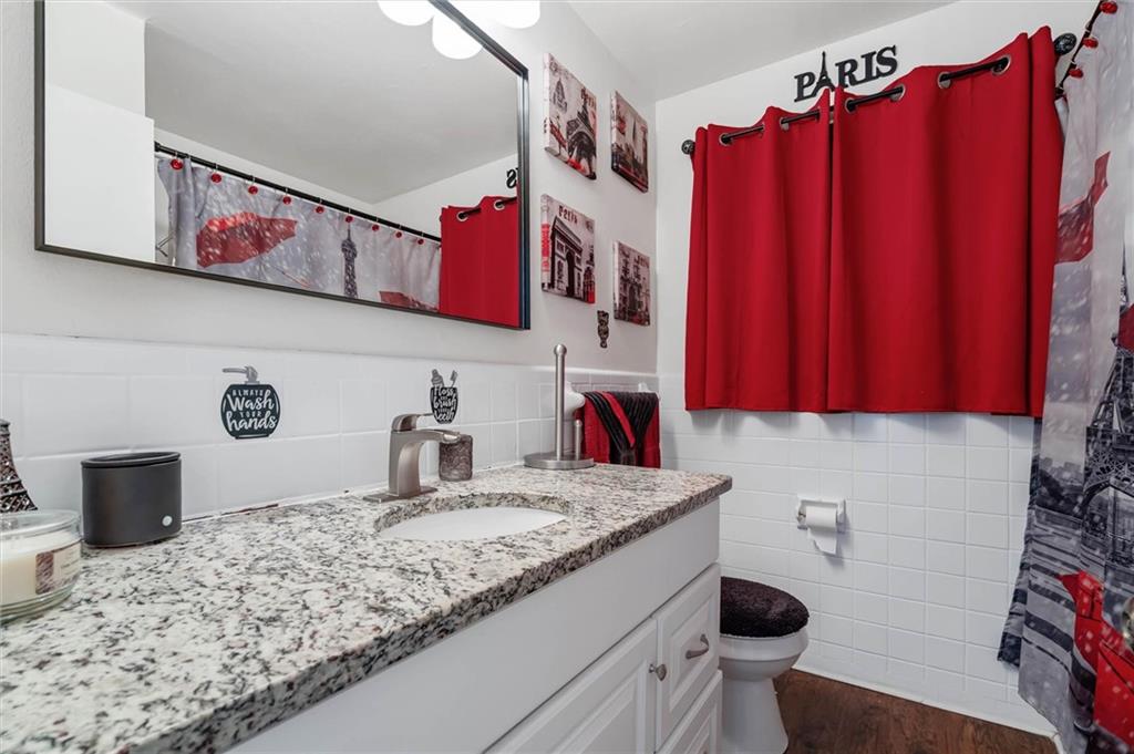 Bathroom with a granite vanity, large mirror, and red Paris-themed shower curtain.