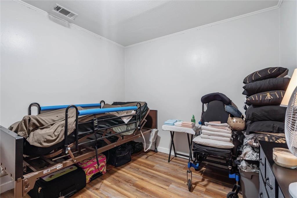 Crowded room with padded adjustable tables, stacked cushions, folded towels, and wood flooring.