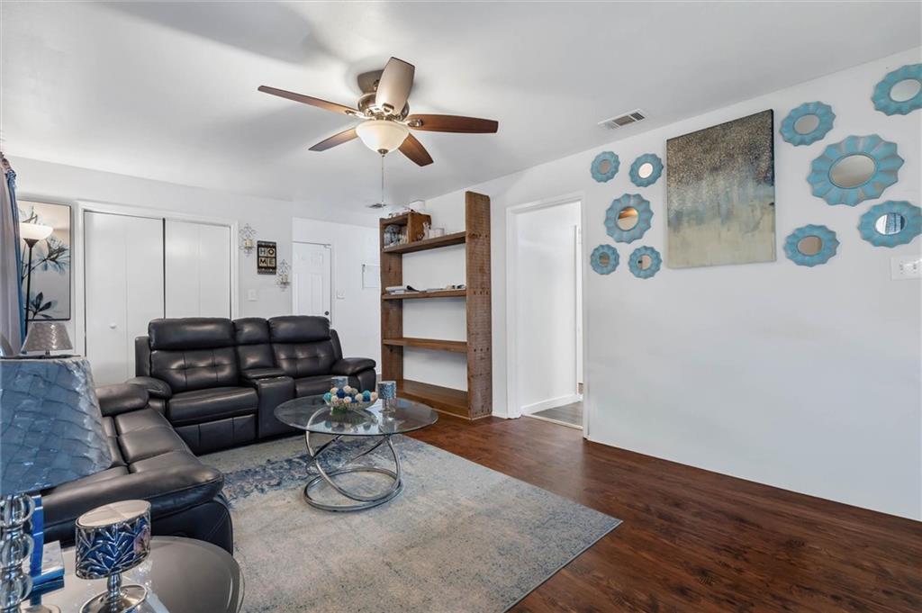Living room with black leather seating, open wooden shelves, and blue wall decor.