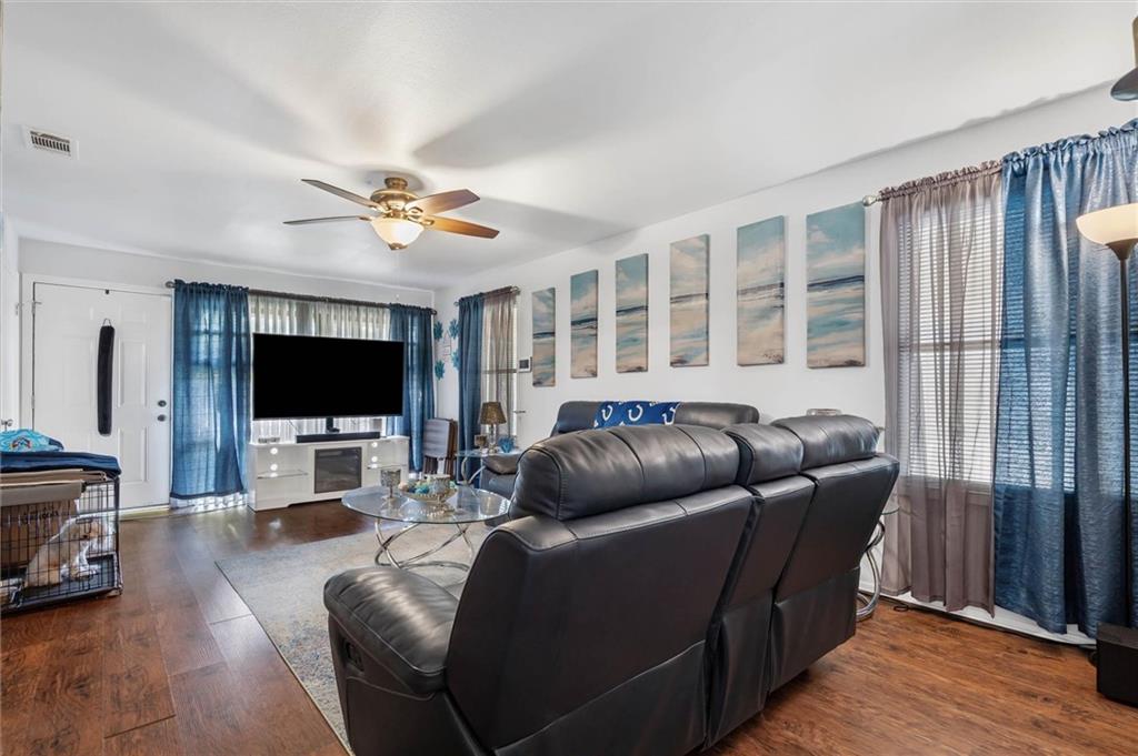 Living room with dark leather recliners, hardwood floors, and coastal wall art.