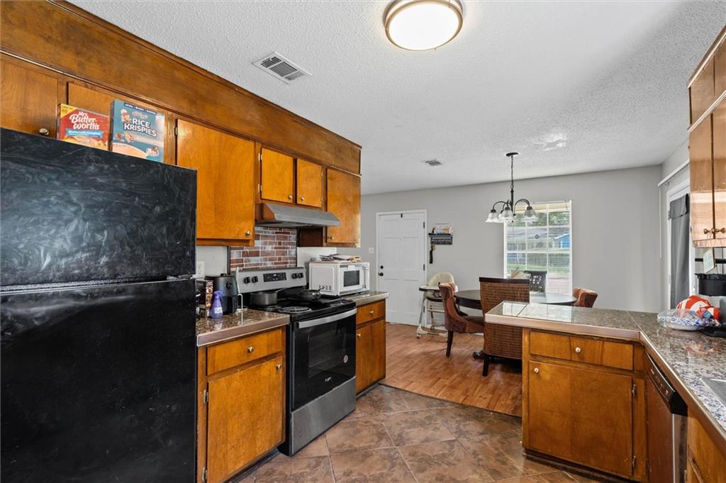 Kitchen with wood cabinets, black appliances, and an adjoining dining area with a table and chairs.