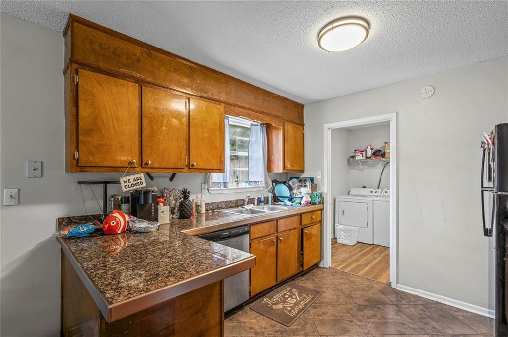 Kitchen with wood cabinets and patterned countertops, opening to a laundry area with a washer and dryer.