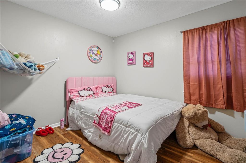 Bedroom with a pink Hello Kitty bed, pink curtains, and a large teddy bear.