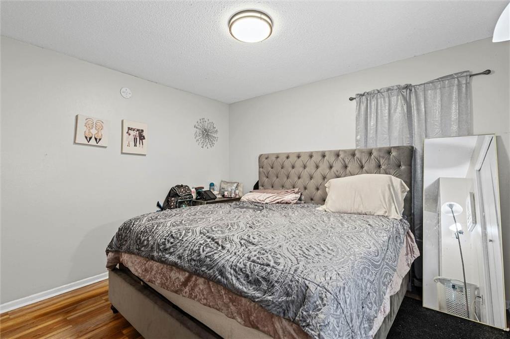 Bedroom with a large bed, tufted gray headboard, patterned bedding, and a full-length mirror.