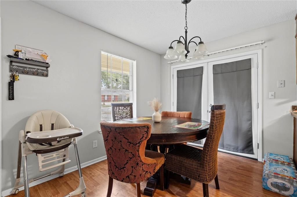 Dining room with a round table, chandelier, and high chair beside curtained glass doors.