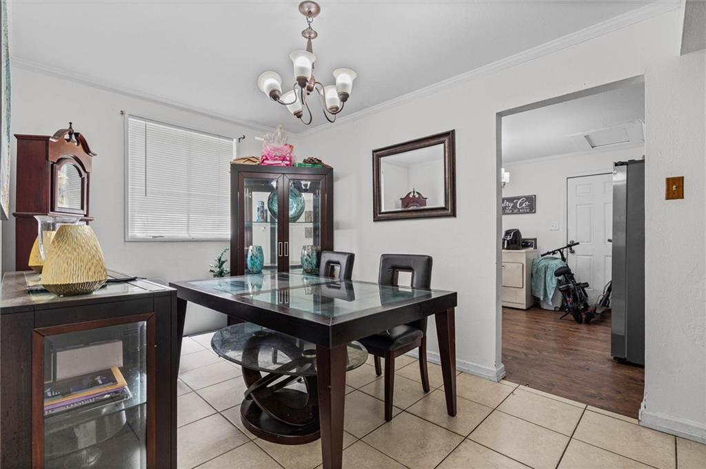 Dining room with a glass-top table, dark wood cabinets, chandelier, and an open doorway to the kitchen.
