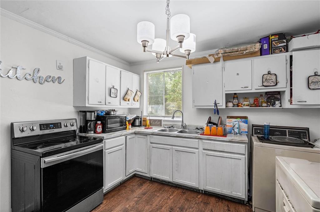 Kitchen with white cabinets, two ranges, a double-basin sink, and dark wood flooring.