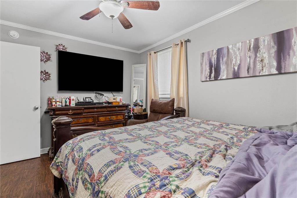 Bedroom with a patchwork quilt-covered bed, dark wooden dresser, and wall-mounted television.