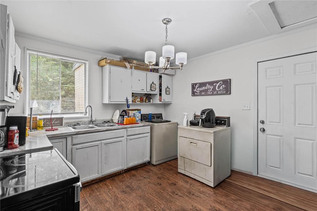Laundry room with white cabinets, a utility sink, washer, and dryer.