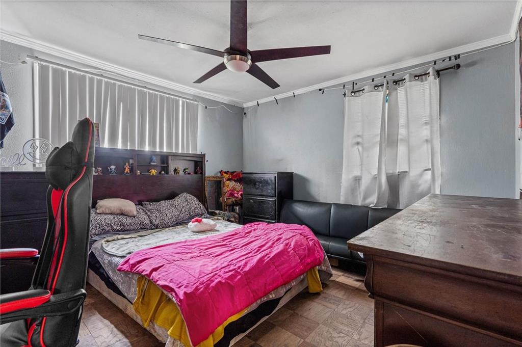 Bedroom with a bright pink bedspread, black-and-red gaming chair, and large wooden desk.