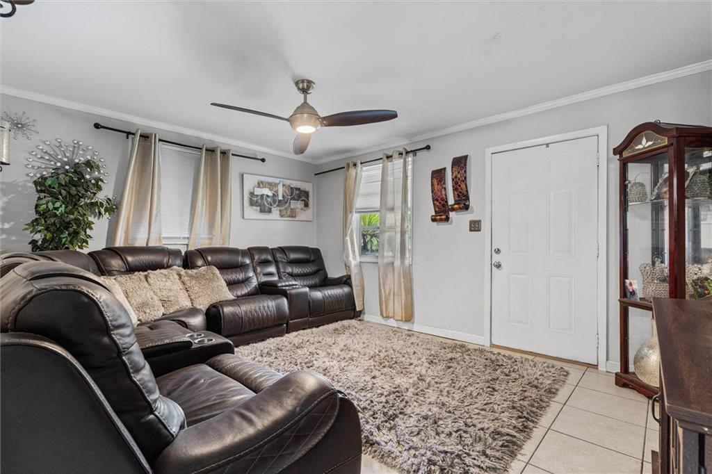Living room with black leather sectional sofas, a shag rug, and a ceiling fan.