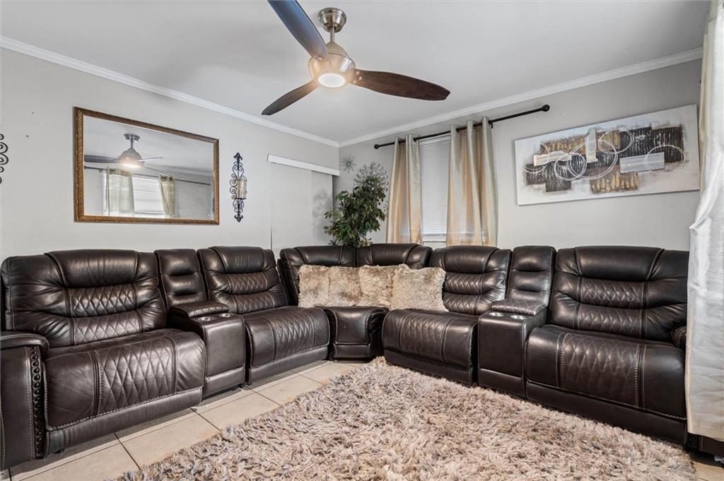 Living room with a dark leather sectional, ceiling fan, and shag rug.