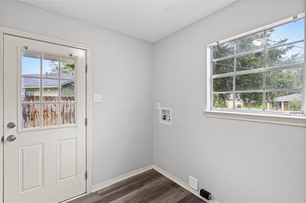 Vacant laundry room with washer hookups, a window, and a white exterior door.