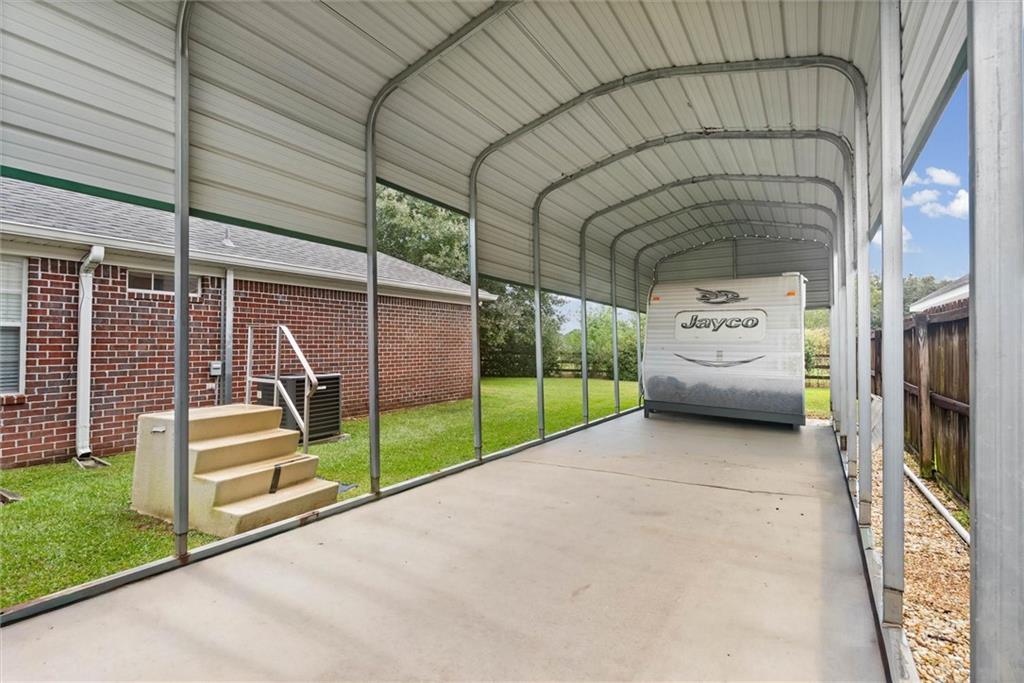 RV carport with a Jayco trailer parked beside a brick house.