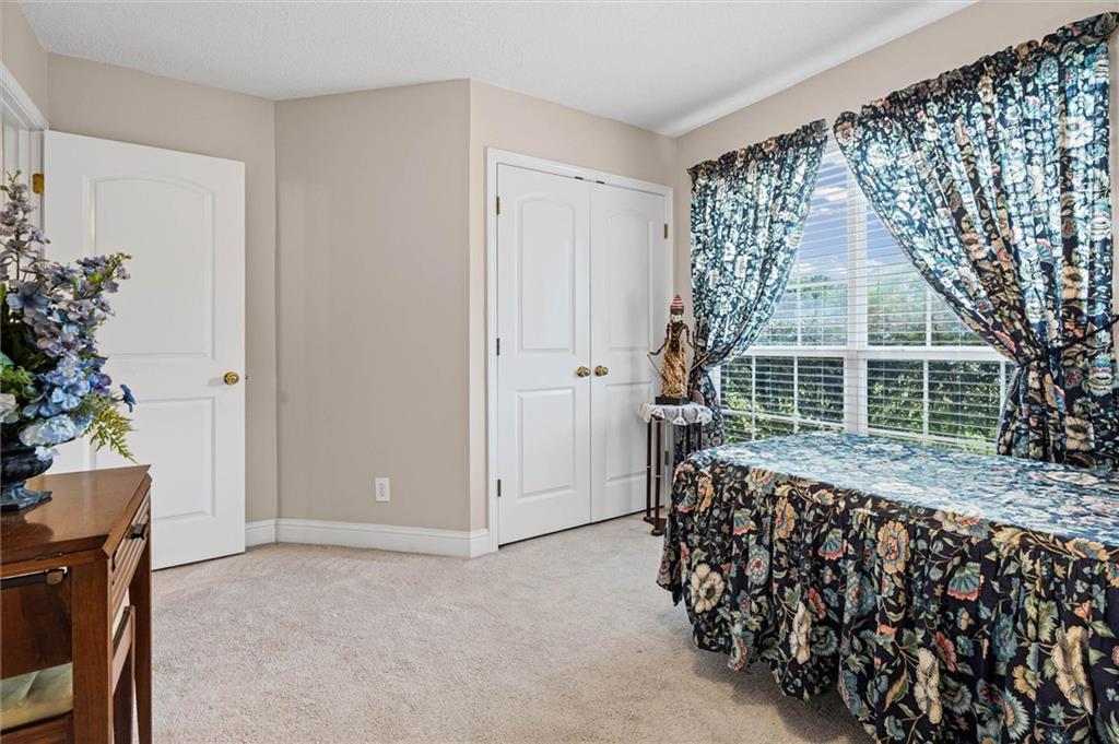 Bedroom with floral bedspread and curtains beside a large window.