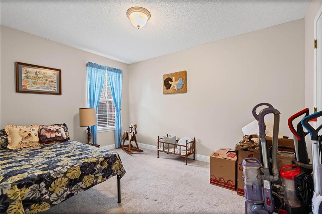 Bedroom with a floral bedspread, blue window curtains, a wooden cradle, and moving boxes.