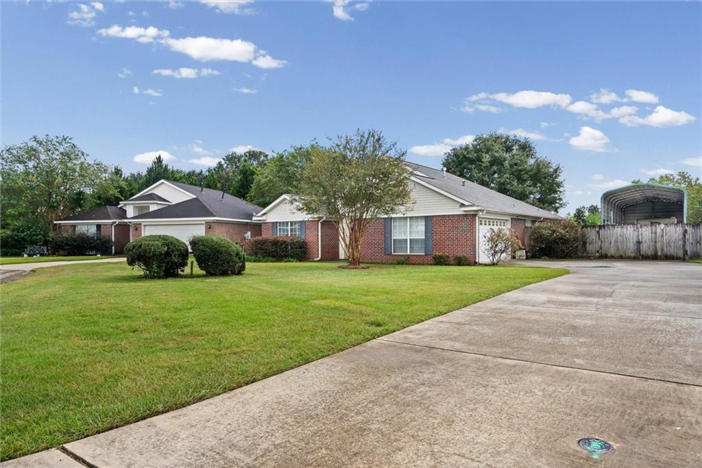 Single-story brick house with a broad driveway and landscaped front lawn.