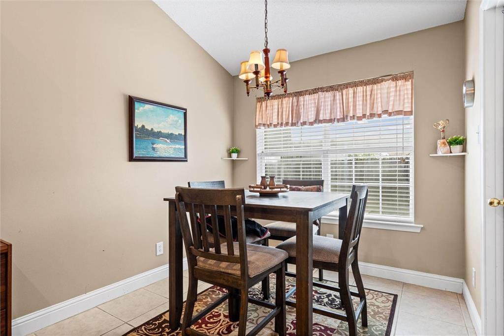Dining room with a dark wood table, patterned rug, and large window with white blinds.