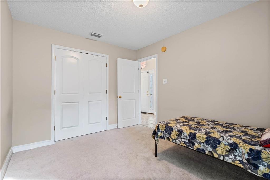 Bedroom with white double closet doors and a partially visible bed with a floral bedspread.