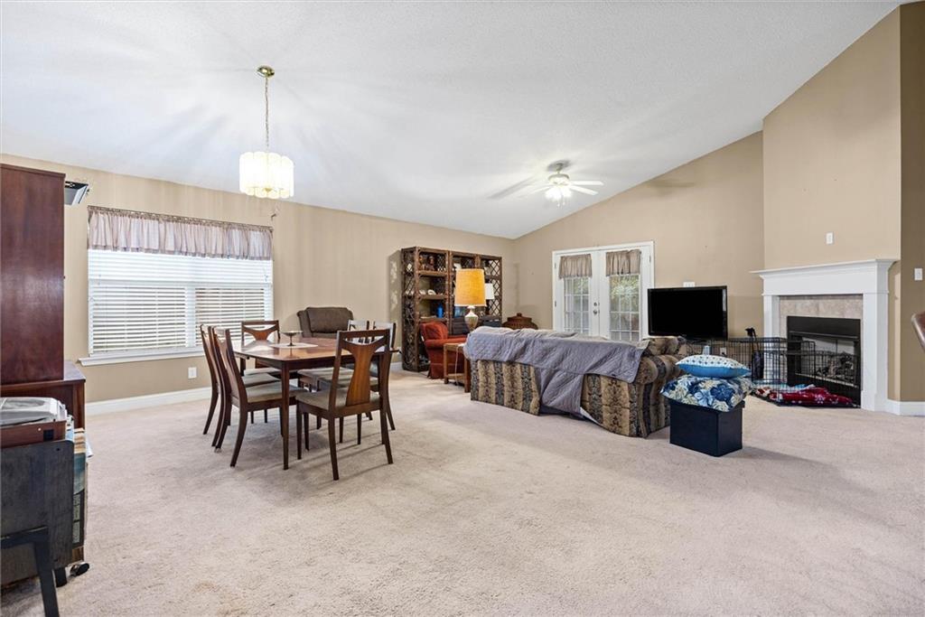 Open living and dining room with a fireplace, French doors, and beige carpeting.