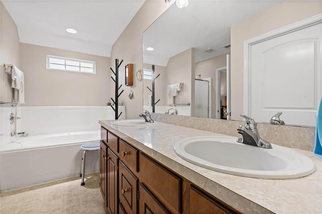Spacious bathroom with a double-sink wood vanity, large mirror, and built-in bathtub.