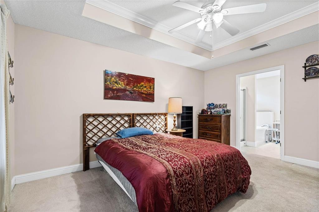 Bedroom with burgundy patterned bedding, a lattice headboard, and a ceiling fan.