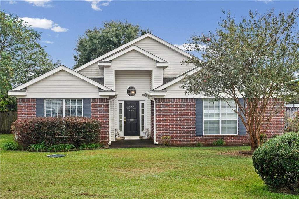 Single-story brick and white-sided home with a gabled entrance, blue shutters, and a broad green lawn.