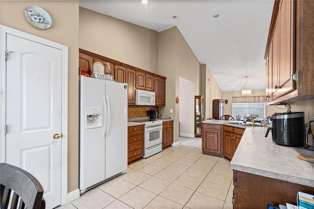 Spacious kitchen with wood cabinets, a central island, and a white side-by-side refrigerator.