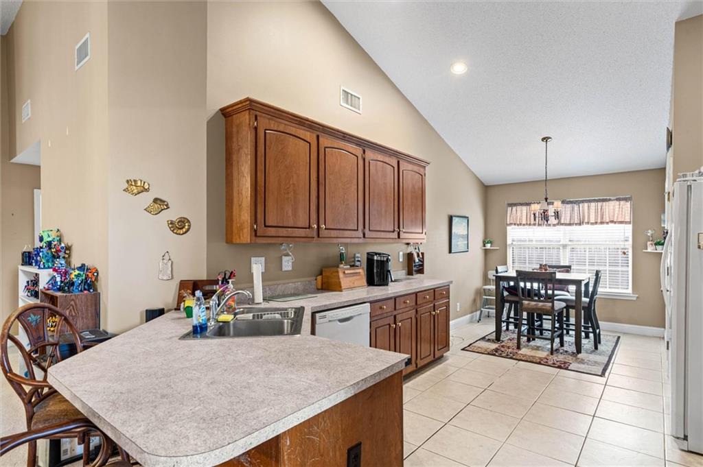 Kitchen with a large sink island and dark wood cabinets opening to a dining area.