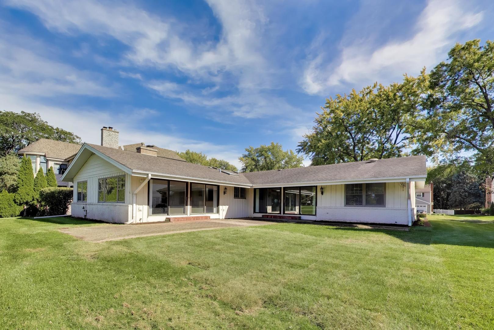 Rear exterior of a single-story home with a screened patio and broad lawn.