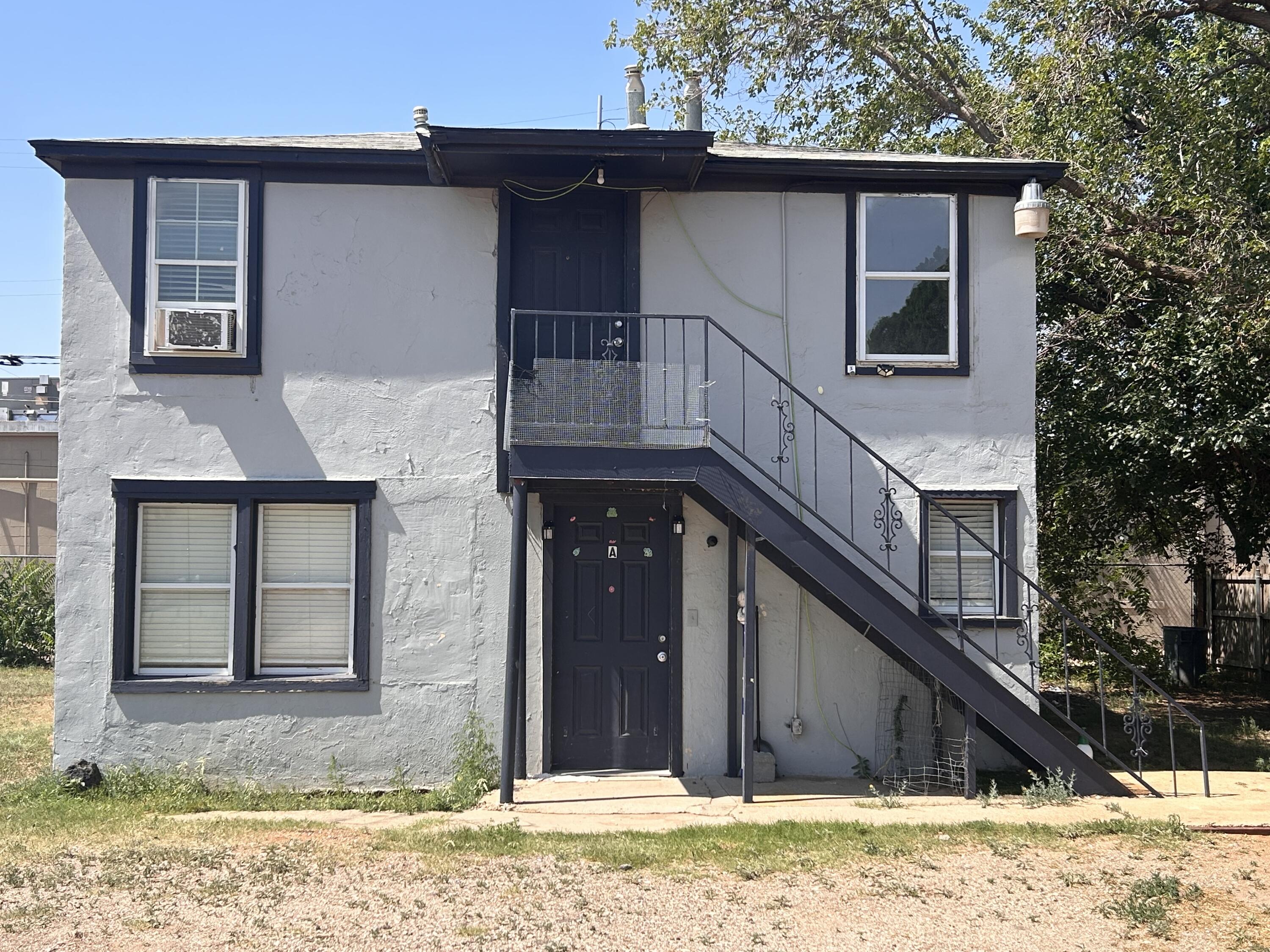 Two-story gray residential building with dark trim and an exterior staircase.