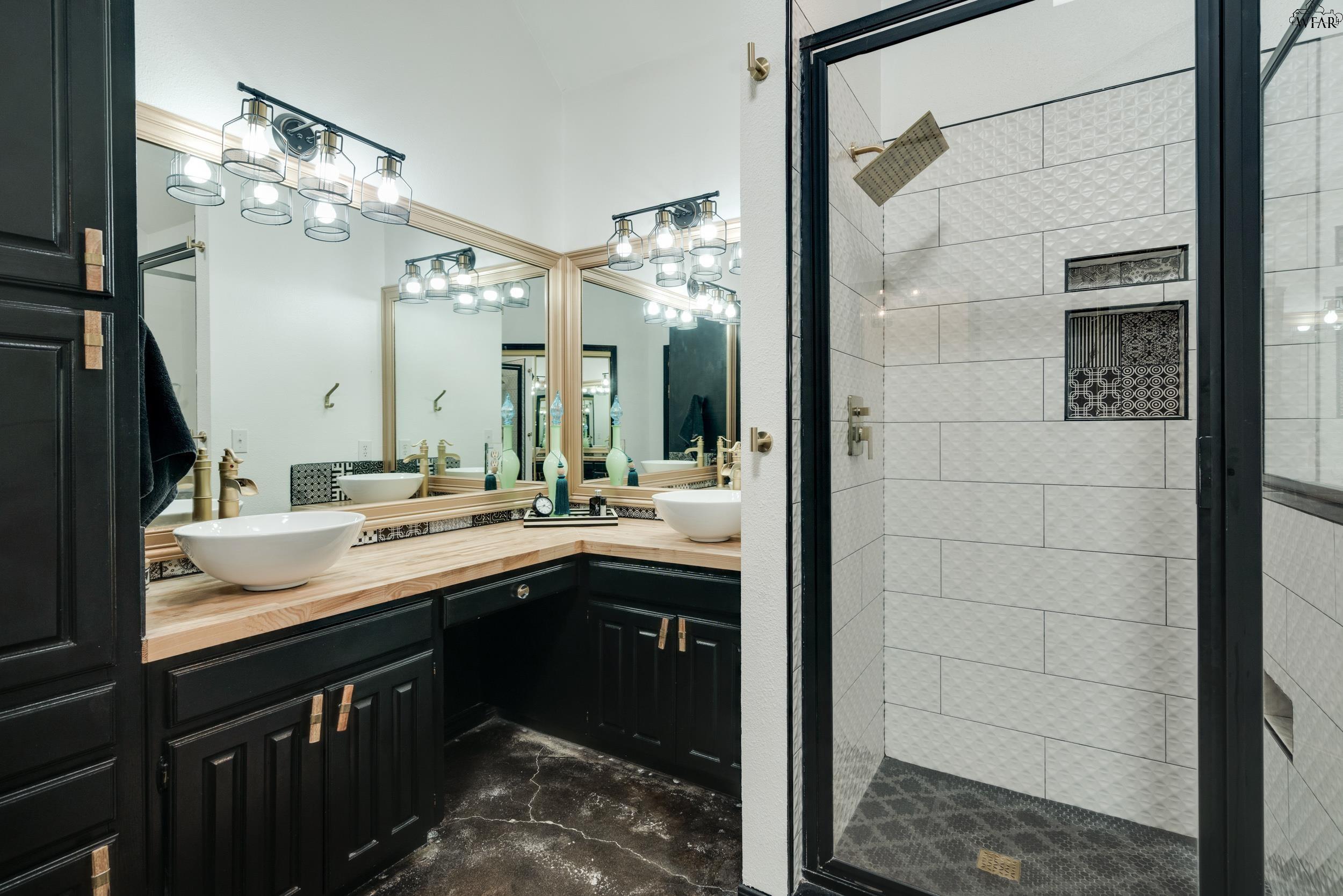 Bathroom with a double vessel-sink vanity and a white tiled walk-in shower.