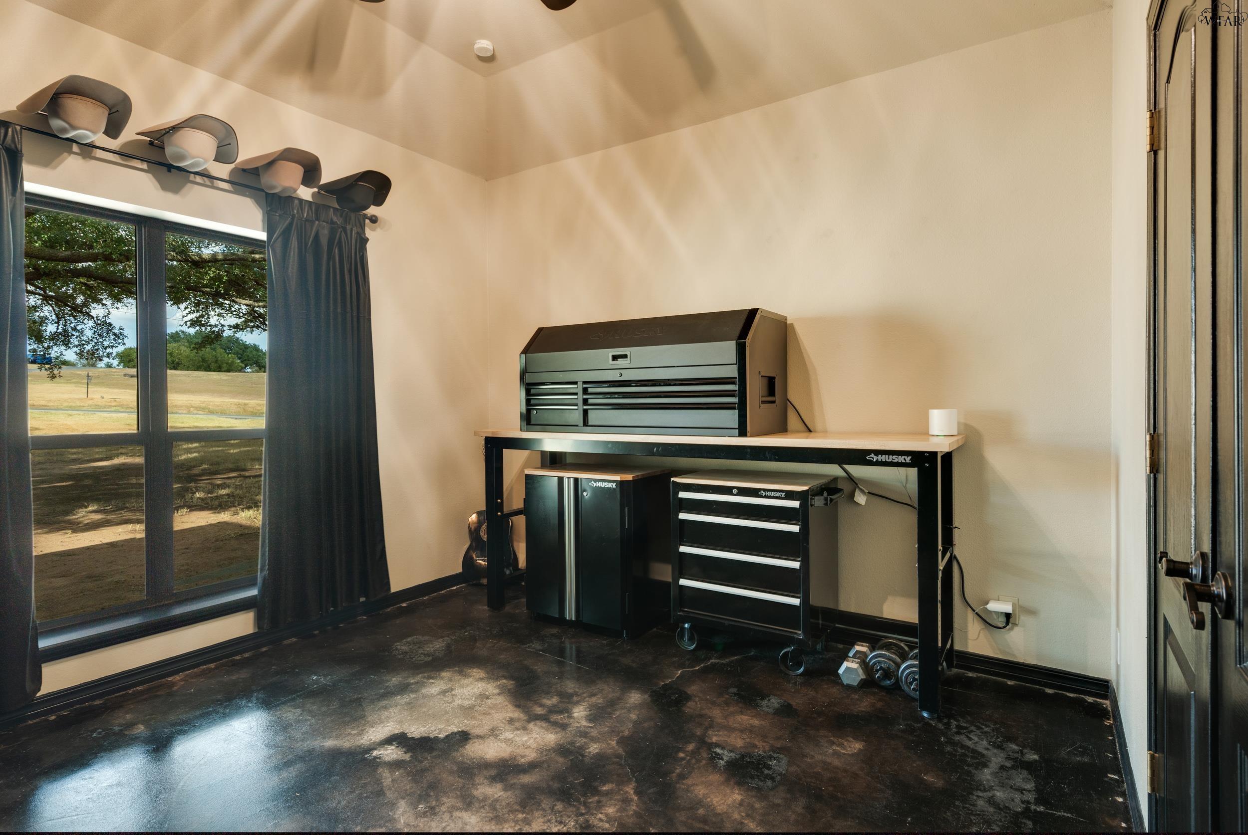 Garage workshop with black tool chests and workbench beside a large window overlooking a field.