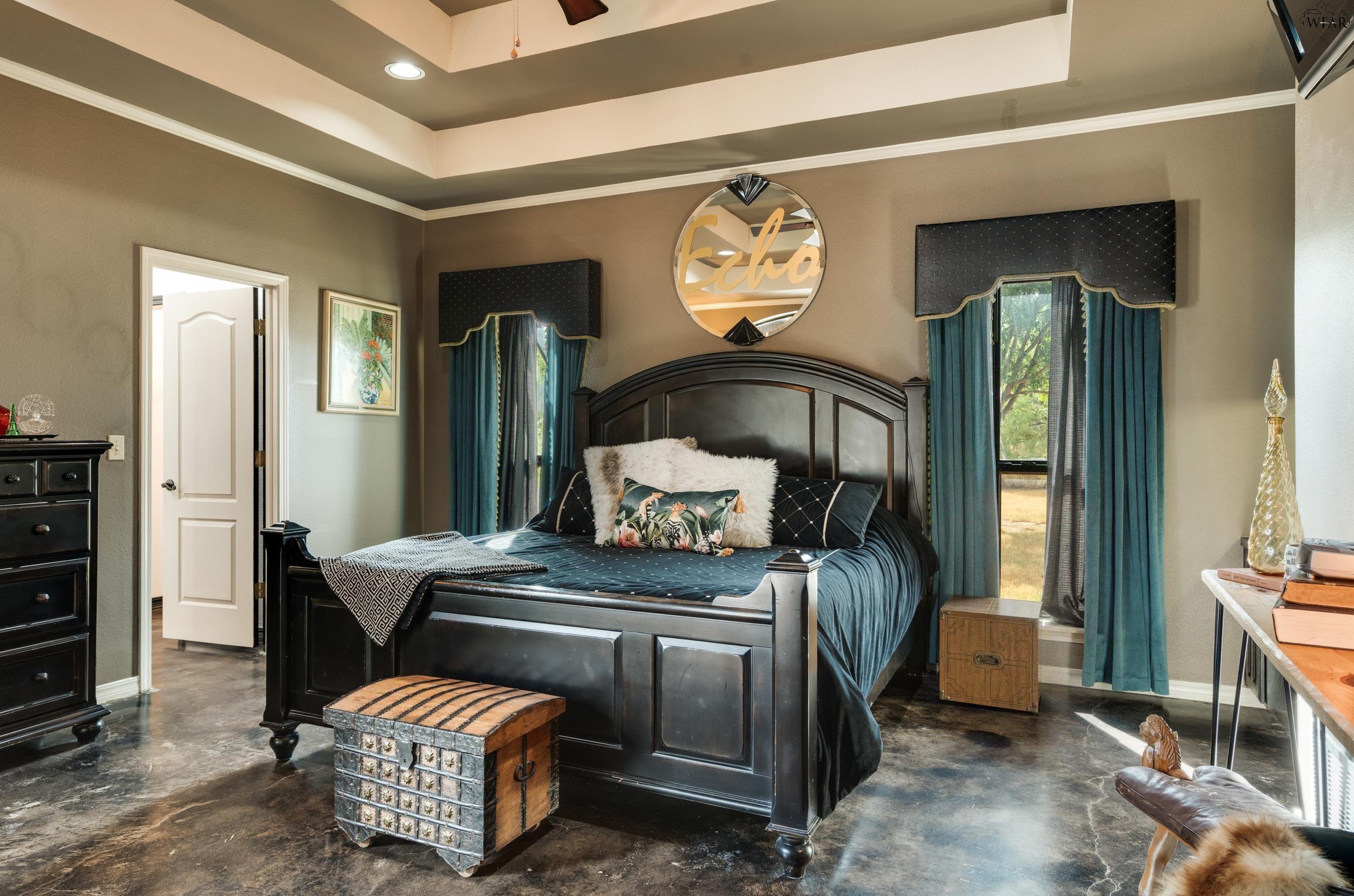 Bedroom with a dark wood bed, teal curtains, and a round mirror above the headboard.
