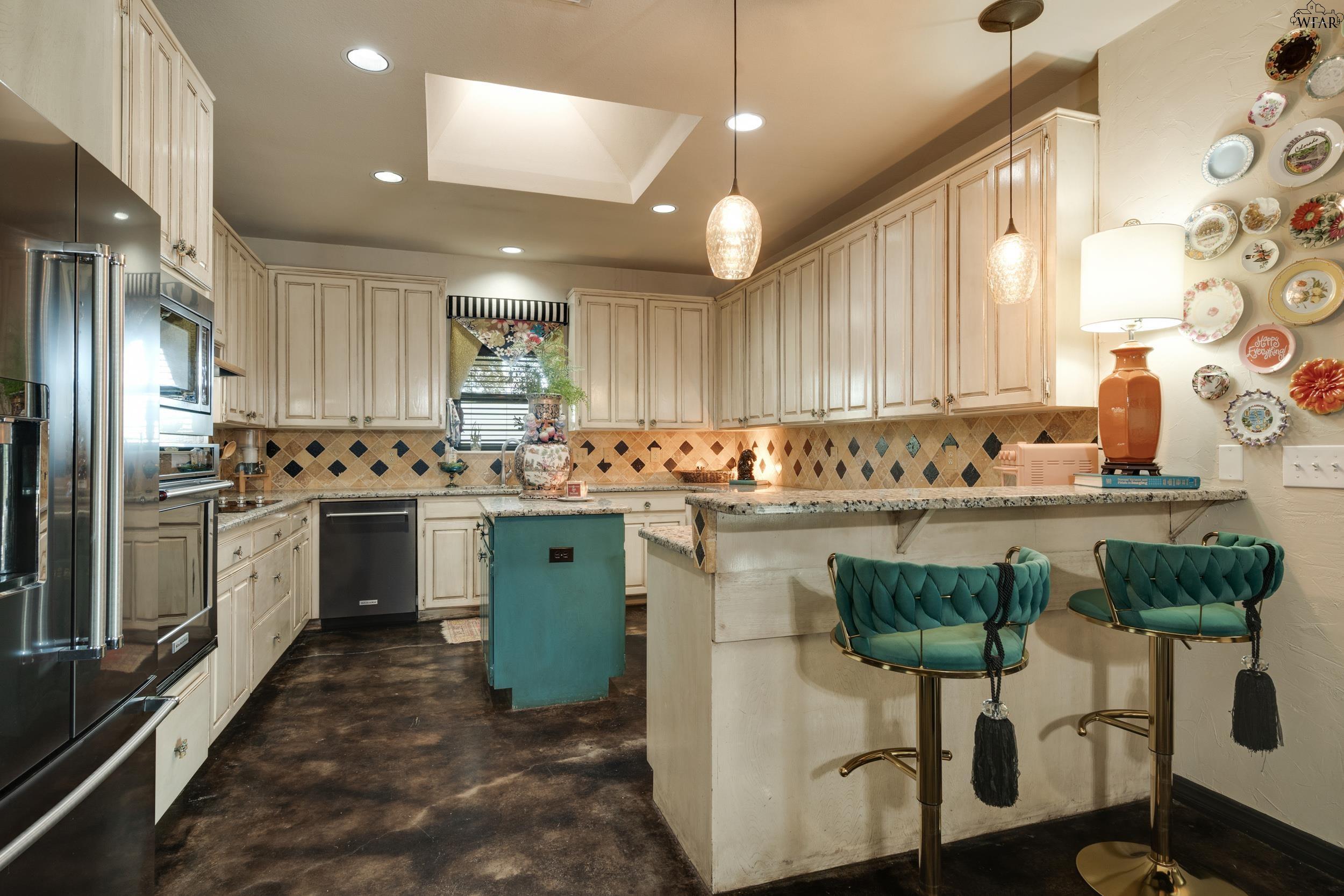 Kitchen with cream cabinetry, a turquoise island, patterned backsplash, and teal breakfast bar stools.
