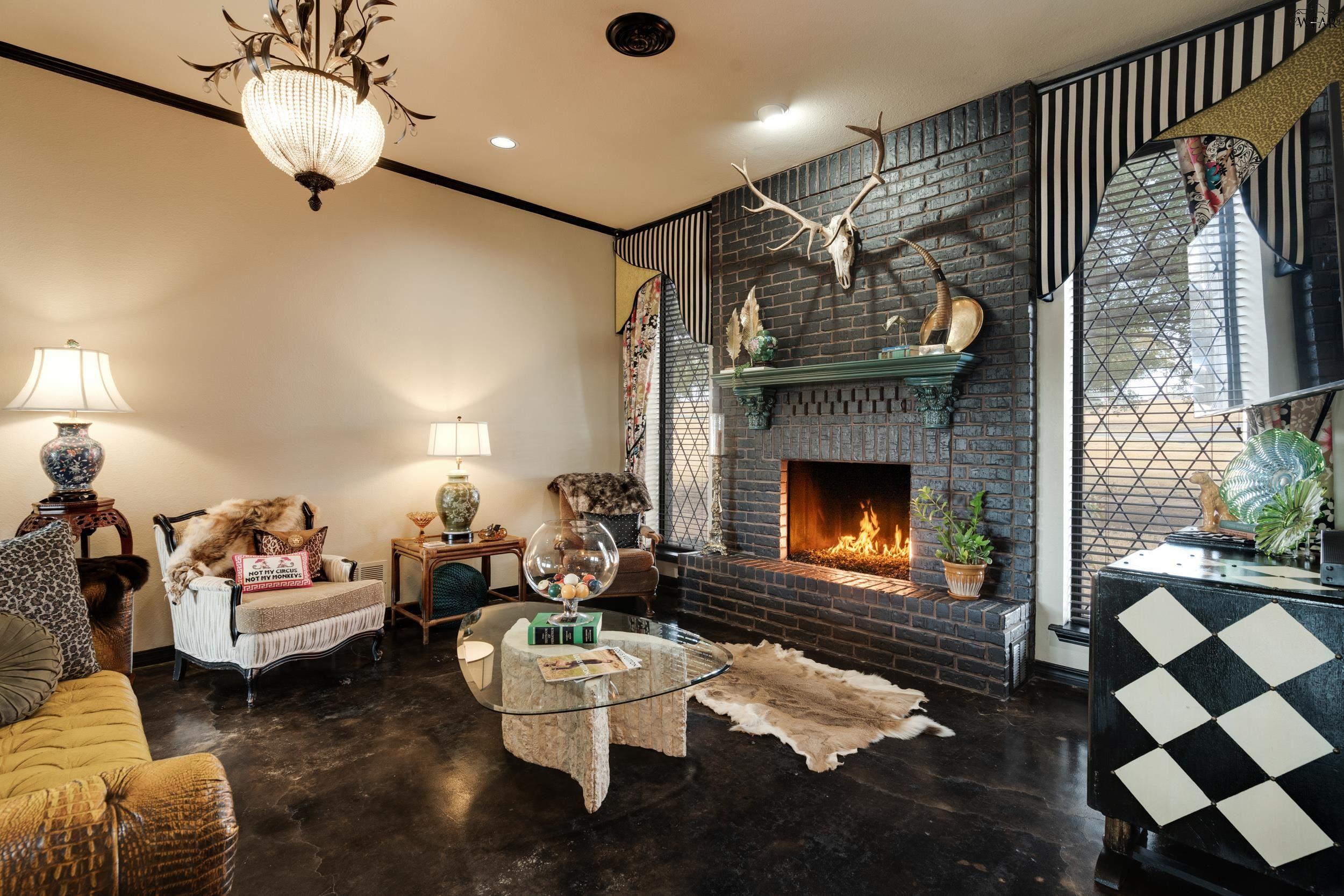 Living room with a lit brick fireplace, arched windows, and eclectic furnishings.