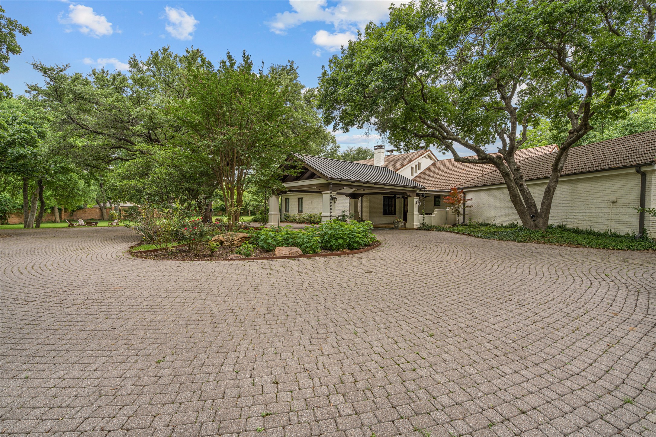 Luxury home with a covered entrance behind a circular cobblestone driveway and landscaped island.