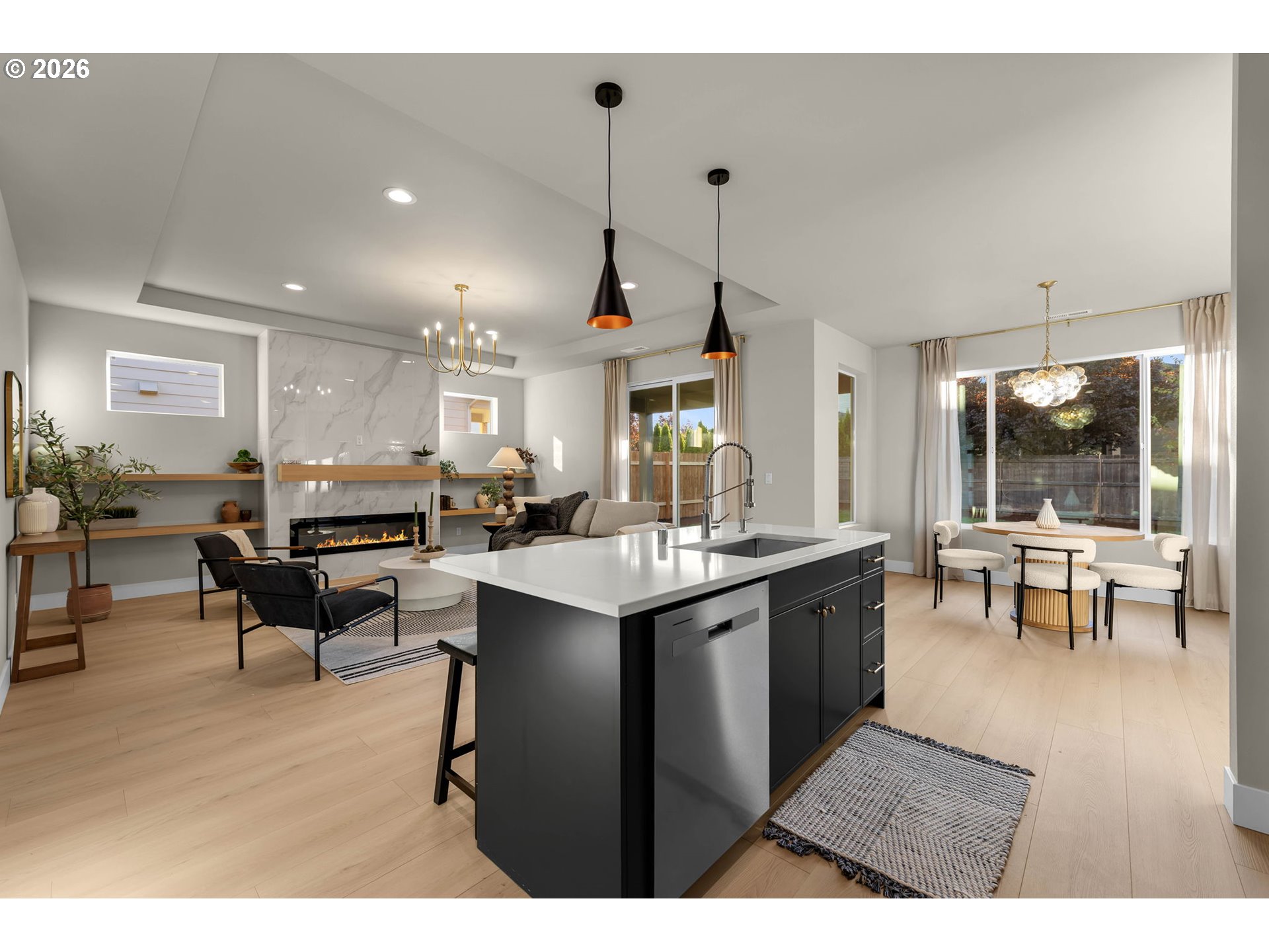 Open-concept kitchen and living area with a dark island, marble fireplace wall, and dining nook.