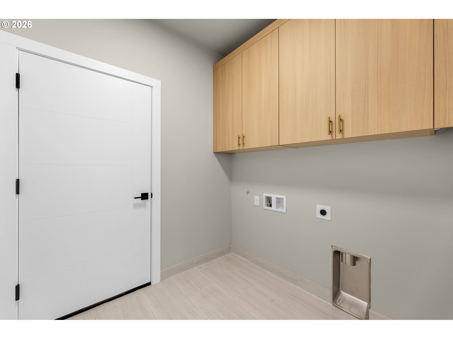Empty laundry room with light wood cabinets, washer and dryer hookups, and a recessed dryer vent.