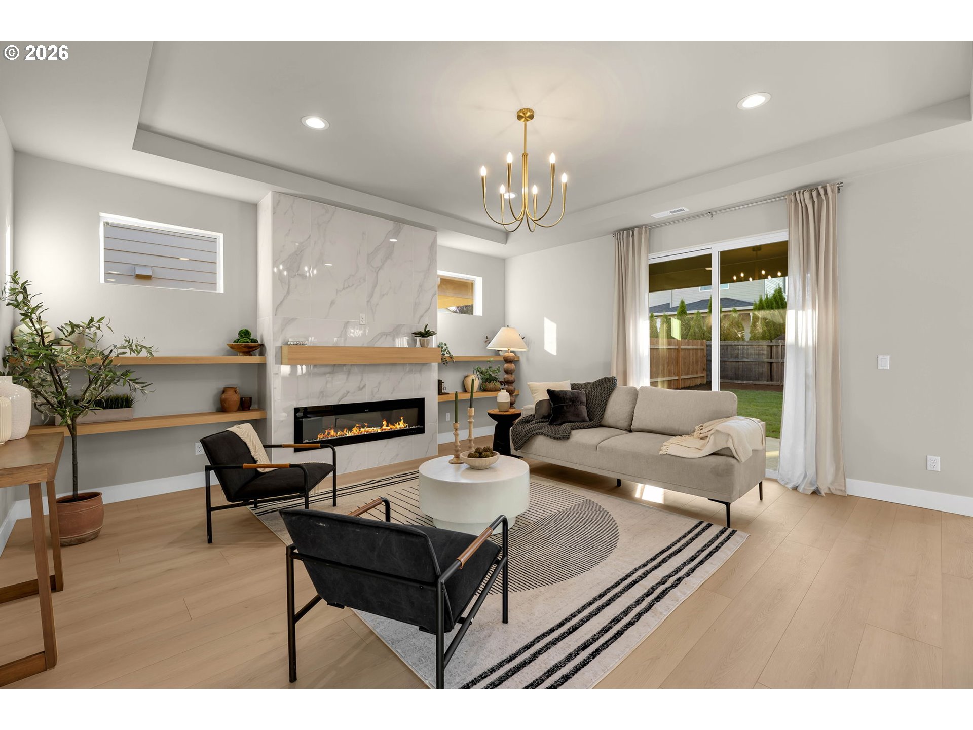 Staged living room with a marble-look fireplace, floating shelves, and sliding doors to the backyard.